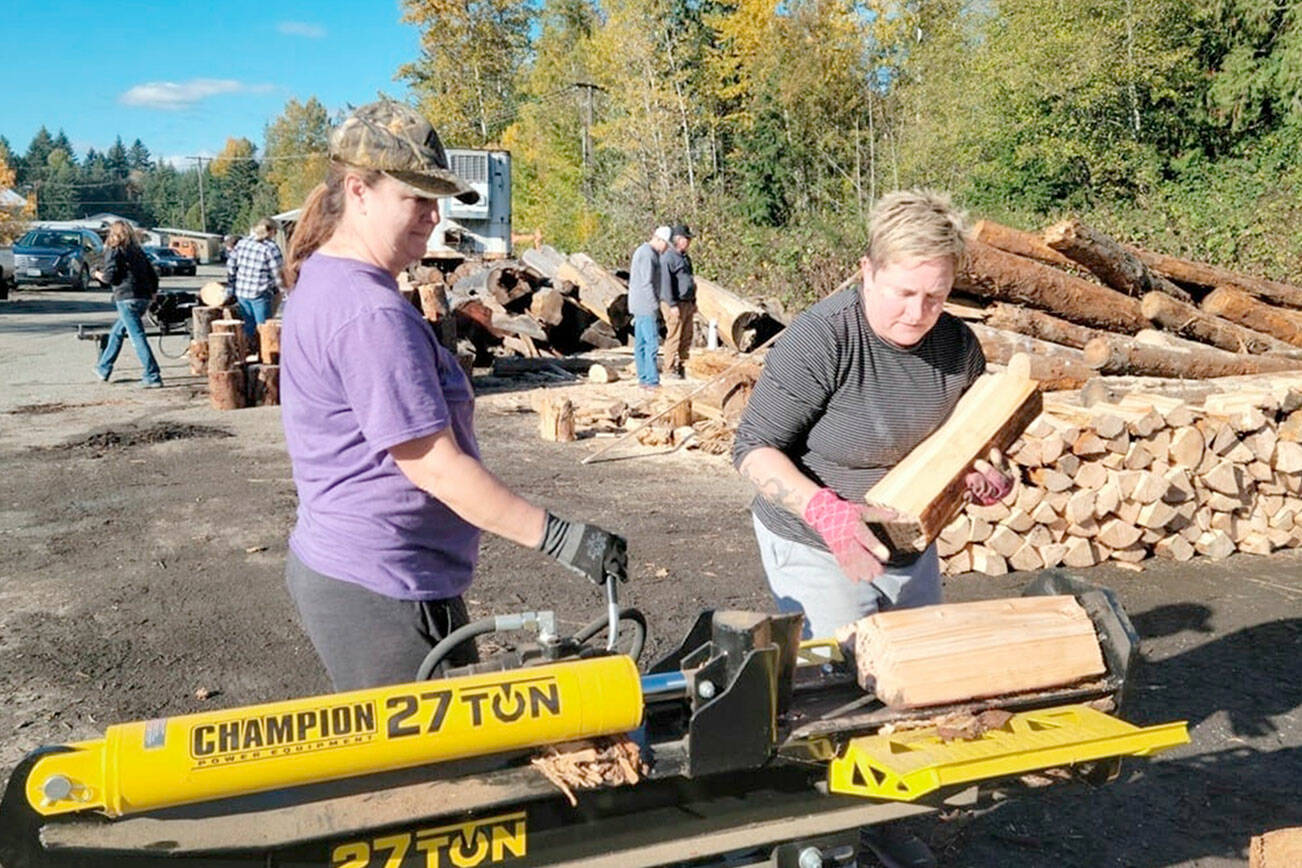 Staci Poythress and Pam Cunningham split logs to raise funds for a graduation party for the Port Angeles High School class of 2022