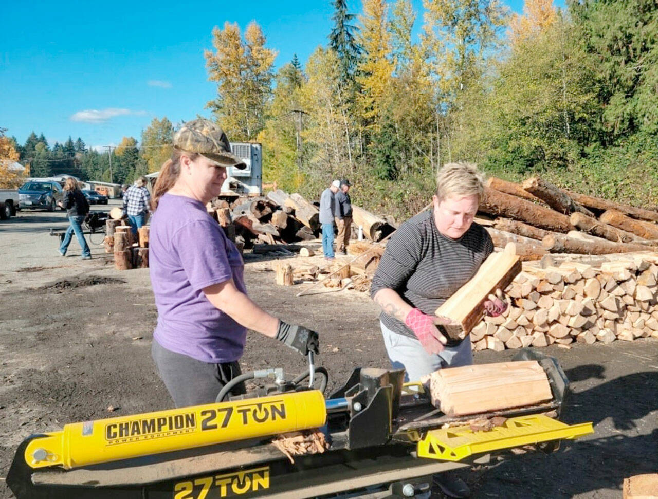 Staci Poythress and Pam Cunningham split logs to raise funds for a graduation party for the Port Angeles High School Class of 2022.