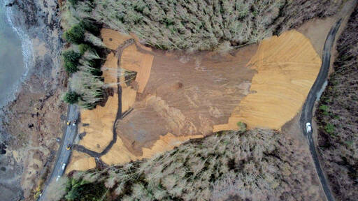 An aerial overview of the slide area shows state Highway 112 at left and a private service road at right. The state Department of Transportation reopened Highway 112 to two-way traffic, although a second slide area still requires about eight weeks of work. (State Department of Transportation)