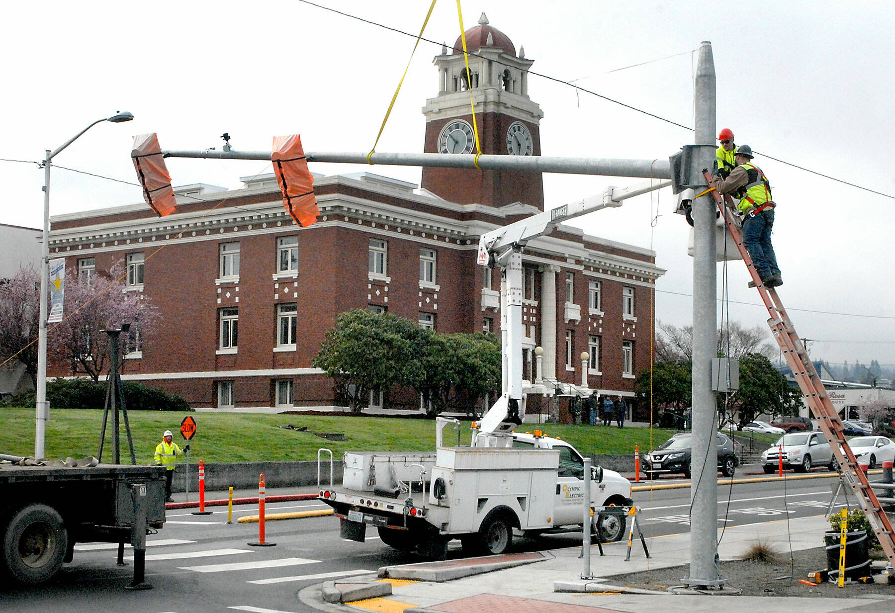 A construction crew installs a new traffic light at the corner of Lincoln and Third streets on Tuesday as a traffic improvement project along South Lincoln Street resumes. The project, which includes traffic dividers, lane revisions, sidewalks and crosswalks, began in 2021 and is expected to now add a traffic light and pedestrian crossing flashing light, with work through mid-April. Motorists can expect periodic detours and traffic delays during construction. (Keith Thorpe/Peninsula Daily News)