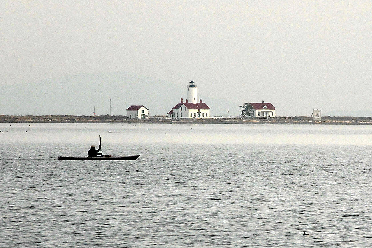 Ken Lincoln of Port Townsend kayaks across Dungeness Bay against a backdrop of the New Dungeness Lighthouse on Saturday north of Sequim. Lincoln said he was paddling out from Cline Spit to meet a group of other kayakers who were putting in at Port Williams. (Keith Thorpe/Peninsula Daily News)