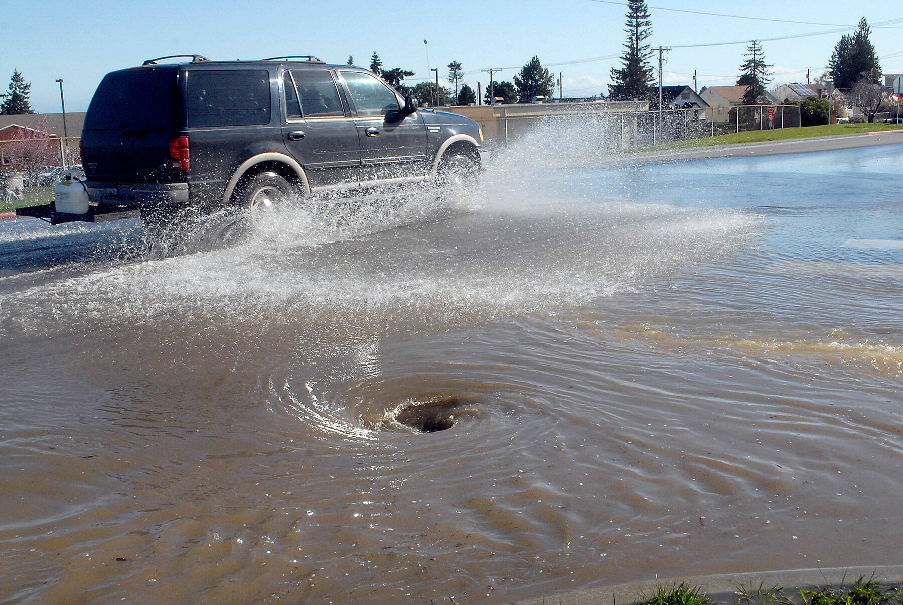 Traffic splashes along East Lauridsen Boulevard as water from a main break flows into a storm drain at South Chase Street on Wednesday after a 6-inch water line burst in the 200 block of East Orcas Avenue in Port Angeles. (Keith Thorpe/Peninsula Daily News)