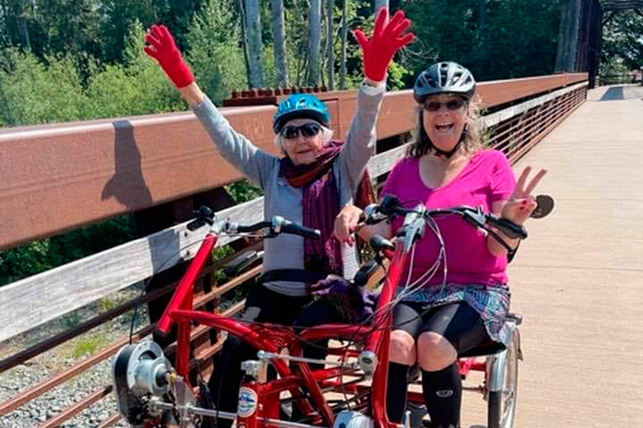 Rita McCabe, left, and Sequim Wheelers Vice President Lanie Cates enjoy a ride on a side-byside tandem bike on the Olympic Discovery Trail. Sequim Wheelers are preparing for their fifth season this spring. (Nicole Lepping)