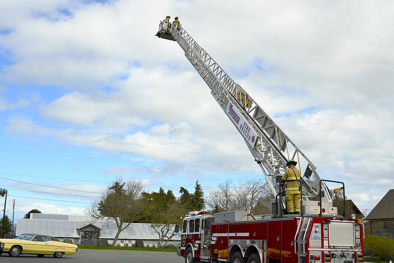 In the bucket of East Jefferson Fire Rescue's new ladder truck, firefighters Matt Sheehan, left, and Ben Richter demonstrate extension of the 95-foot ladder, along with firefighter Andy Dalrymple at the base. Diane Urbani de la Paz/Peninsula Daily News