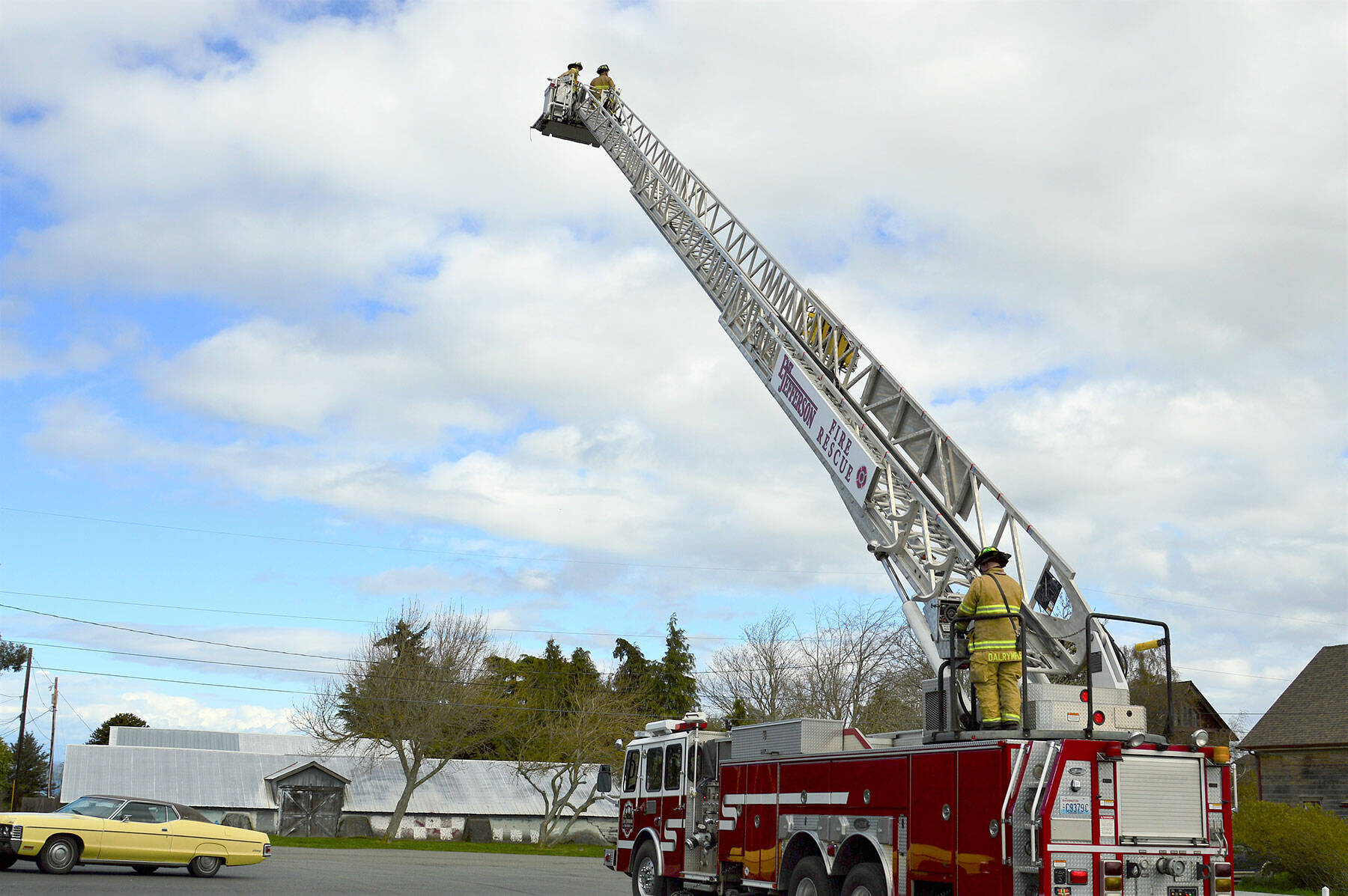 In the bucket of East Jefferson Fire Rescue’s new ladder truck, firefighters Matt Sheehan, left, and Ben Richter demonstrate extension of the 95-foot ladder, along with firefighter Andy Dalrymple at the base. (Diane Urbani de la Paz/Peninsula Daily News)