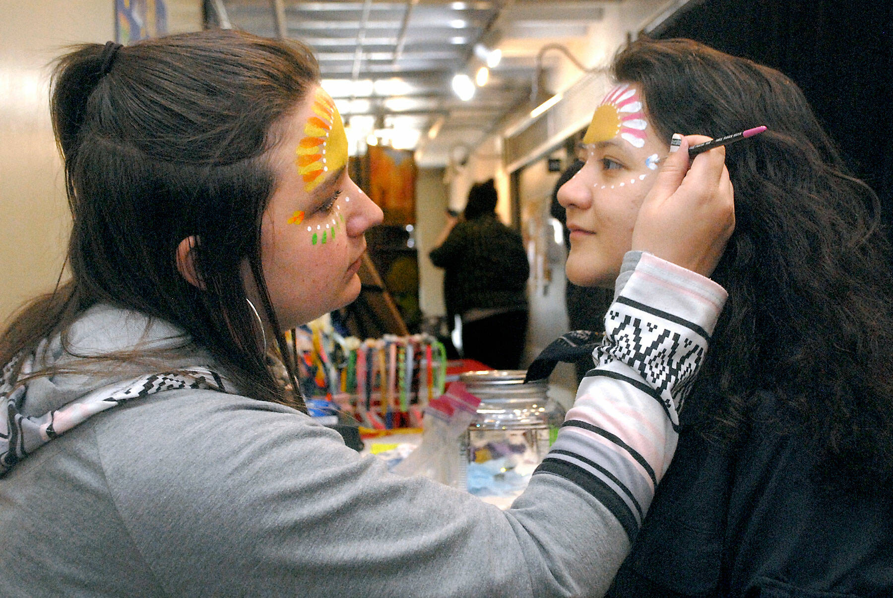 Soohia Art of Port Angeles, right, gets her face painted by Emma Gockerell of Sequim-based Emma-gine Painting & Parties during Fridays pop-up market at the inaugural Squatchcon 2022 Comic & Arts Convention at The Wharf on the Port Angeles waterfront. (Keith Thorpe/Peninsula Daily News)