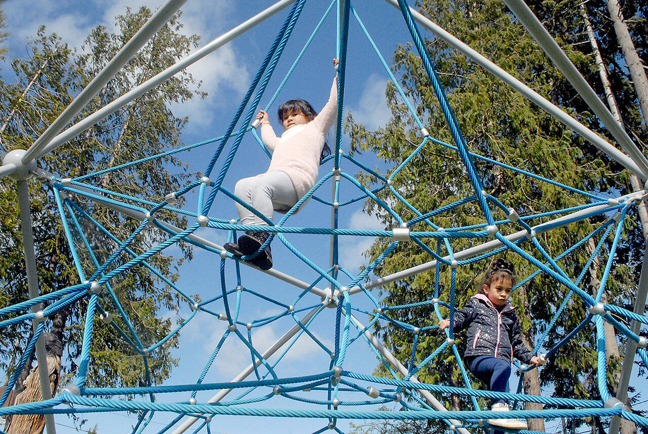 Aria Barrette, 7, top, and her sister, Alyeah Barrette, 5, both of Olympia, spend time on a jungle gym at the Dream Playground in Erickson Park in Port Angeles on Saturday. The pair were in Port Angeles visiting relatives and took an afternoon to visit the playground. (Keith Thorpe/Peninsula Daily News)