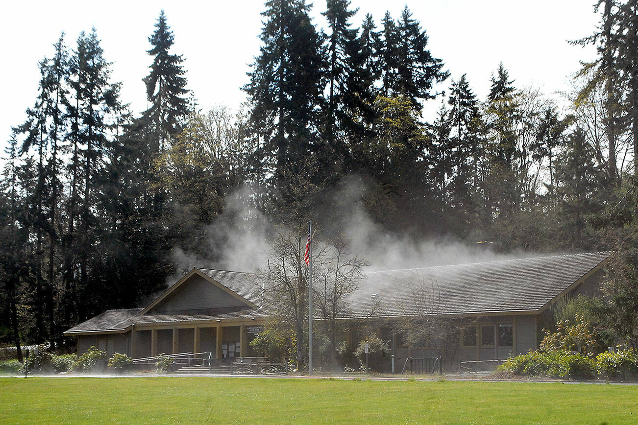 Keith Thorpe/Peninsula Daily News
Steam rises from the roof and front driveway of the Olympic National Park Visitor Center on Thursday in Port Angeles after direct sunlight reached its rain-drenched shingles. Unsettled weather and below-normal temperatures are expected into next week in most areas of the North Olympic Peninsula.