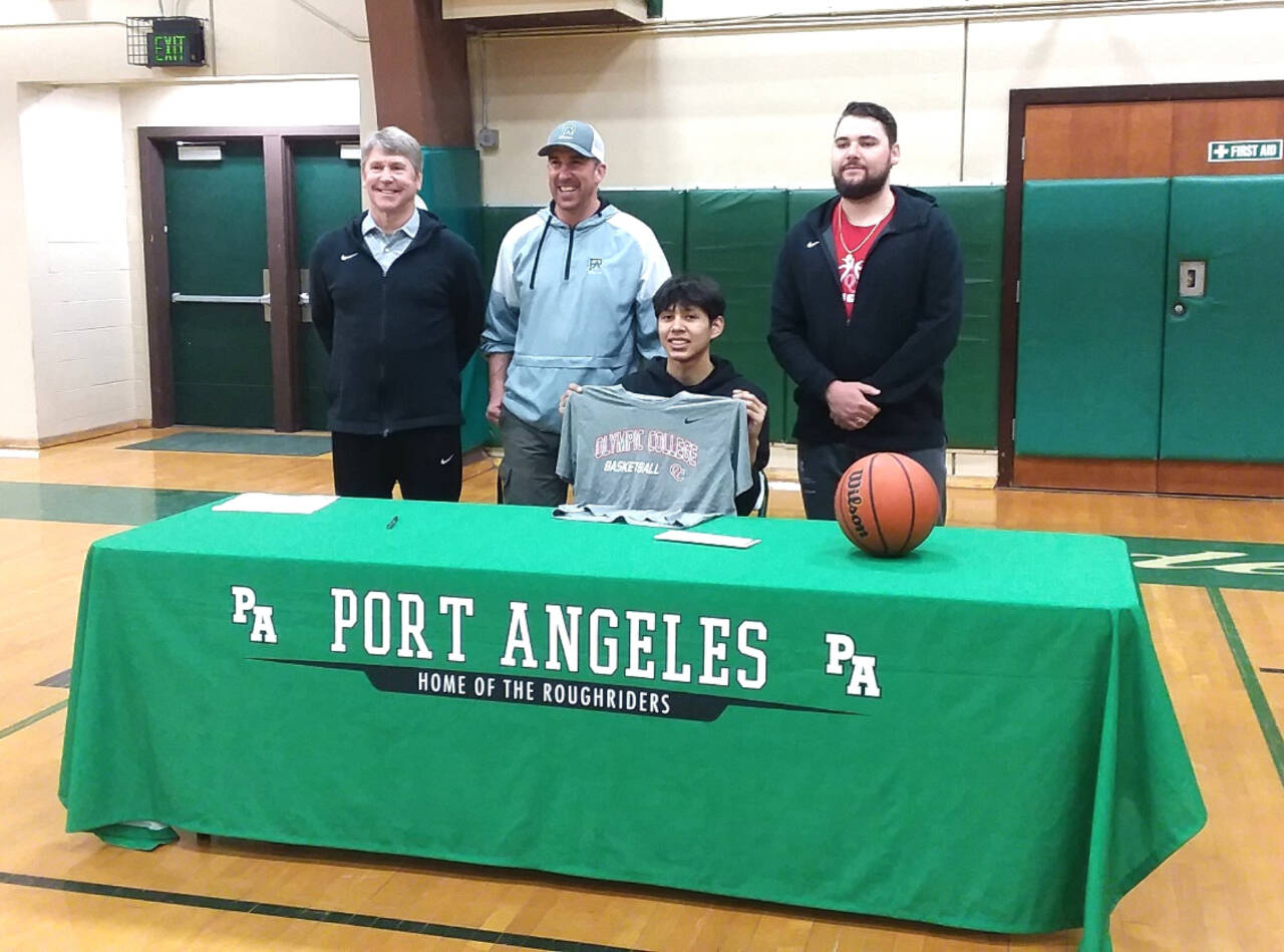 Port Angeles High School basketball player Quanah Wheeler, seated, signs to play for Olympic College last week. Standing from left, are Olympic College men's assistant coach John Callaghan, Port Angeles boys basketball coach Kasey Ulin and Olympic College men's coach Ryley Callaghan. (Pierre LaBossiere/Peninsula Daily News)