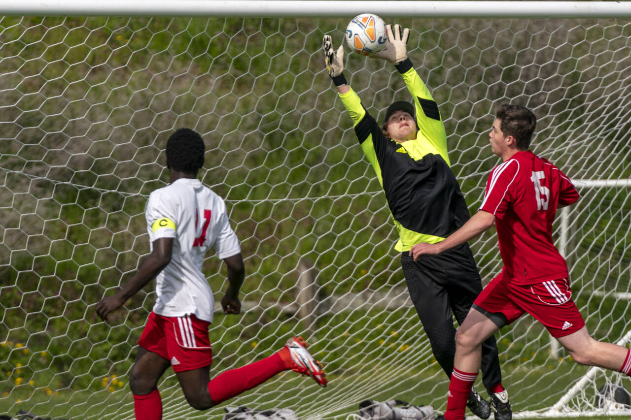 East Jefferson goalkeeper Haven McMillen makes a leaping save against Seattle Christian during a game Saturday at Memorial Field in Port Townsend. Seattle Christian’s forward Olara Parodi, 11, and East Jefferson's Micajah Shifflett, 15, were in on the play. Steve Mullensky/for Peninsula Daily News