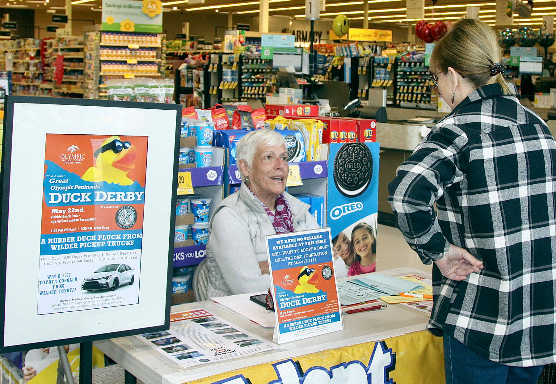 Marielle Eykeman, a volunteer, sells a Duck Derby ticket to Vonda Hartman at the downtown Safeway earlier this week. This year’s Duck Derby will be on the Port Angeles waterfront. (Dave Logan/for Peninsula Daily News)