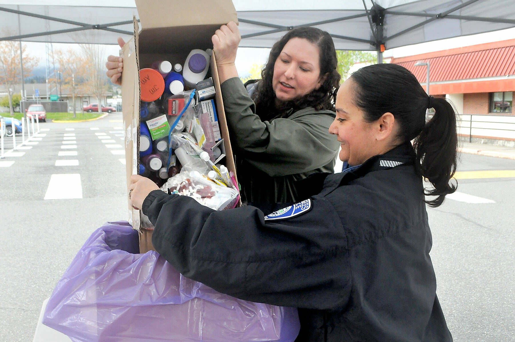 Nicole Salim, evidence manager for the Clallam County Sheriff’s Office, left, and Detective Swift Sanchez of the Port Angeles Police Department dump medicines into a collection box during National Prescription Drug Take Back Day on Saturday at a drop-off site at the Clallam County Courthouse in Port Angeles. At the event, people were allowed to anonymously bring in expired, unused and unwanted prescription drugs for safe disposal. Similar drop-off sites on the North Olympic Peninsula were set for Sequim, Quilcene and Port Hadlock. (Keith Thorpe/Peninsula Daily News)