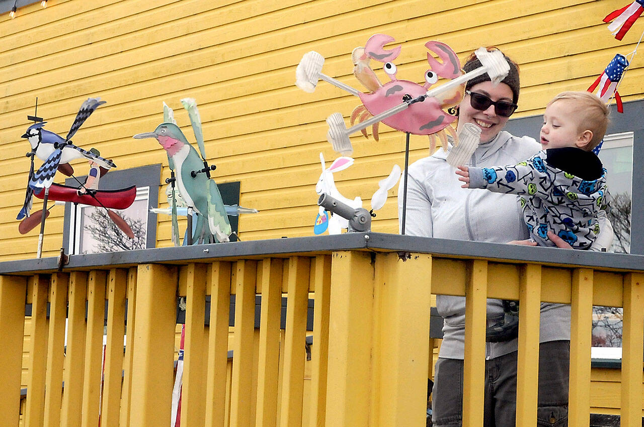 Alisha Teater of Port Angeles watches as her son, William, 14 months, who is fascinated by decorative wind spinners on display on the porch of Pacific Rim Hobby on Saturday in Port Angeles. The pair was on a family shopping excursion with a stop at the hobby store. (Keith Thorpe/Peninsula Daily News)