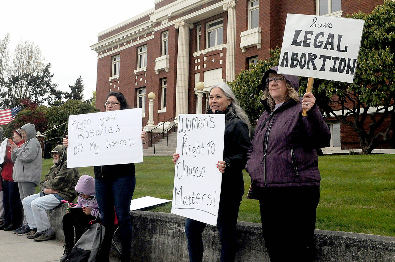 Reproductive rights supporters, from left, Tawny Bagby, Jill Coughenour and Janet Ferris, all of Port Angeles, hold signs protesting the possible overturning of the Roe v. Wade by the U.S. Supreme Court during a gathering on Tuesday in front of the Clallam County Courthouse. About 60 people took part in the event. (Keith Thorpe/Peninsula Daily News)