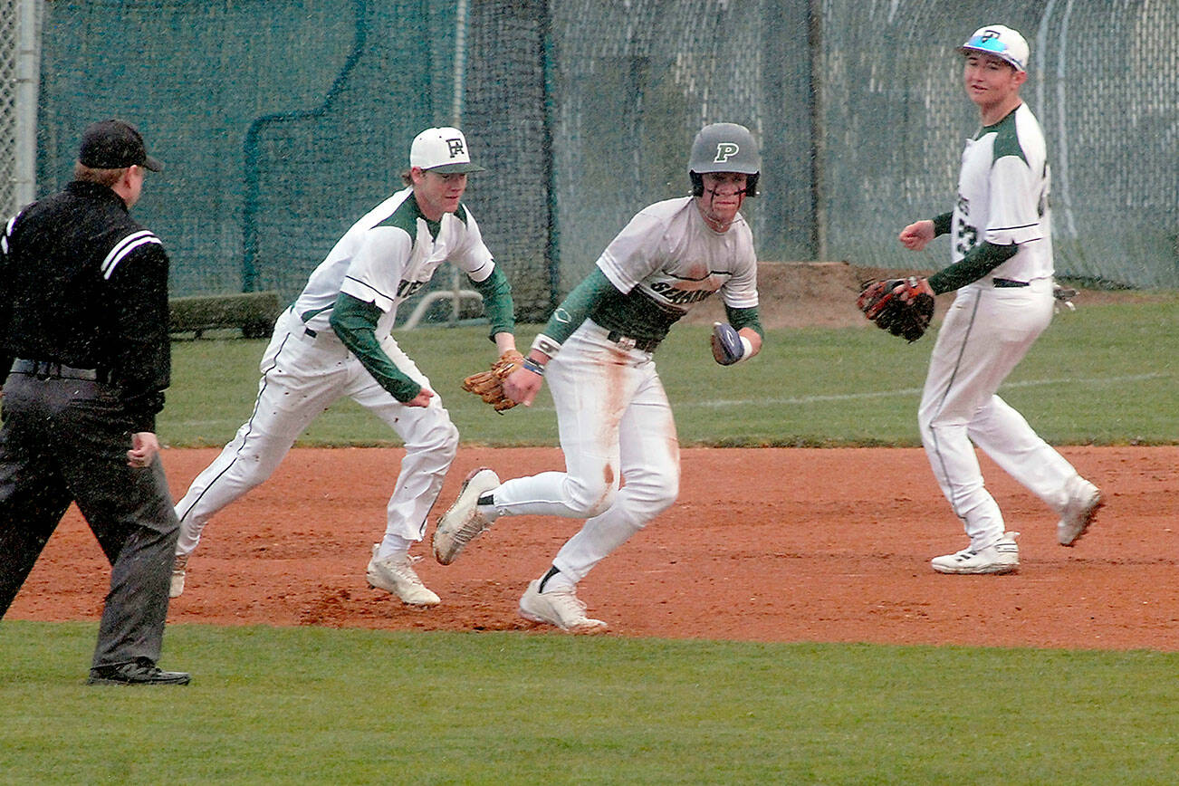 Keith Thorpe/Peninsula Daily News
Peninsula baserunner Payton Knowles, center, gets chased by Port Angeles shortstop Michael Soule as second baseman Colton Romero looks on after Knowles was caught in a rundown between second and third and eventually tagged out in the first inning on Friday at Port Angeles Civic Field.
