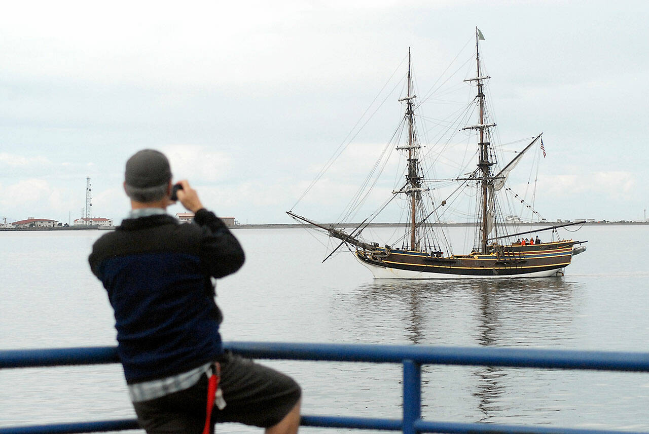 Christopher Thomsen of Port Angeles takes a cellphone photo of the tall ship Lady Washington as it does a beauty pass of City Pier after arriving in Port Angeles in June 2019. (Keith Thorpe/Peninsula Daily News)