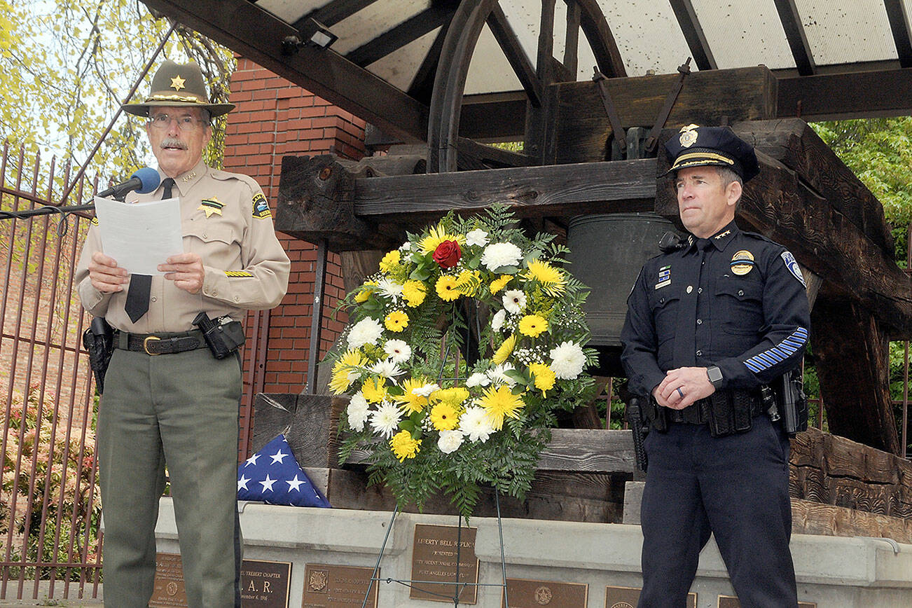 Keith Thorpe/Peninsula Daily News
Clallam County Sheriff Bill Benedict, left, reads off the names of Washington law enforcment officers killed in the line of duty as Port Angeles Police Chief Brian Smith looks on during a ceremony of Friday honoring law enforcement personnel as part of National Police Week. The ceremoney, held at the Liberty Bell replica at Veterans Park in Port Angeles, included music from the Port Angeles High School choir, a flag ceremony, a gun salute and ringing of the bell.