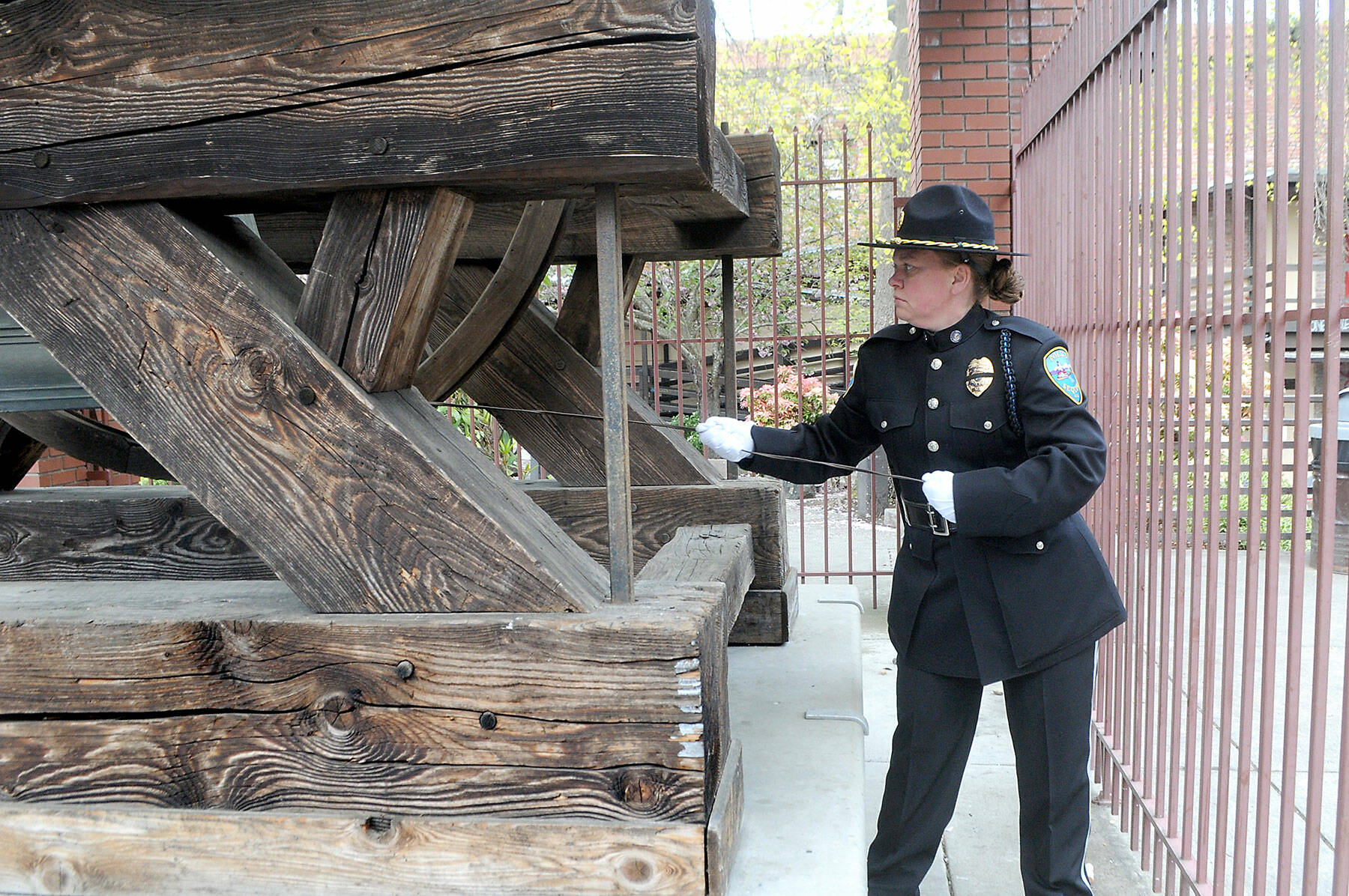 Sequim Police Sgt. Carolee Edwards pulls a cord to ring the Liberty Bell replica to honor fallen law enforcement officers during Friday’s recognition ceremony at Veteran’s Park in Port Angeles. (Keith Thorpe/Peninsula Daily News)