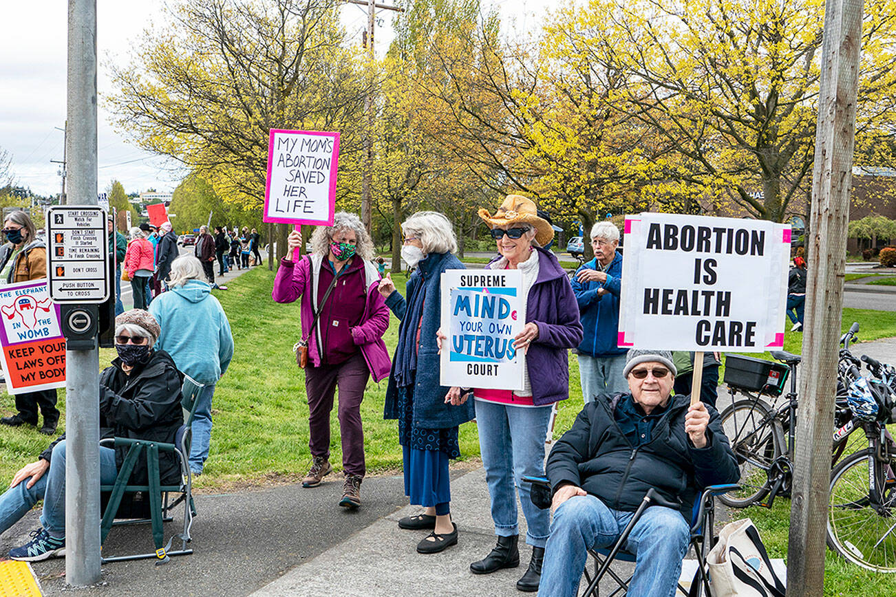Linda Martin, center, from Port Townsend, stands beside her husband Mike Cornforth on the corner of Kearney and state Highway 20 in Port Townsend. Martin, with PT Indivisible, collaborated with Planned Parenthood, the American Civil Liberties Union and Women’s March to stage a rally on Saturday to protest the possible U.S. Supreme Court decision to overturn the 50-year-old Roe v Wade decision guaranteeing the right to abortion. About 250 people from as far away as Seattle and Sequim took part in the rally. (Steve Mullensky/for Peninsula Daily News)