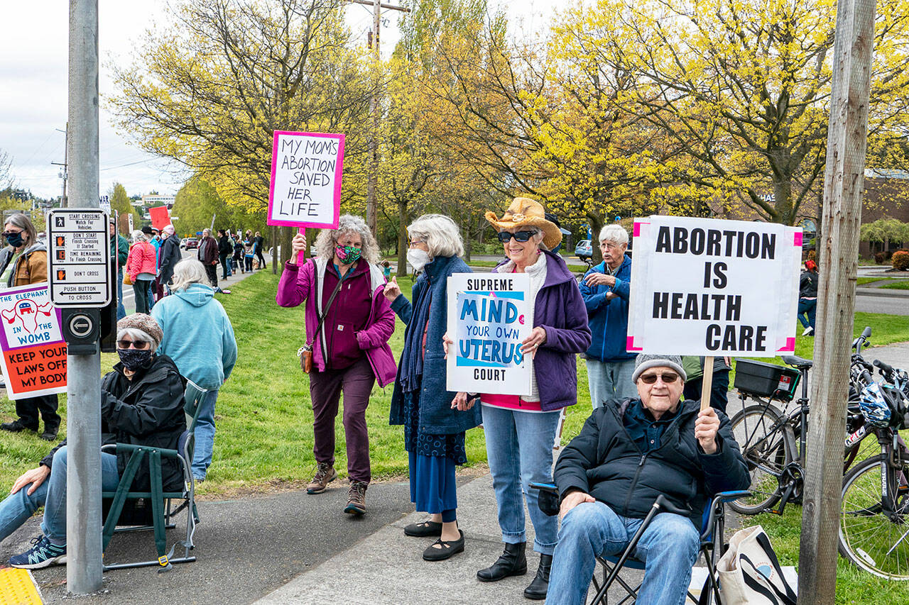 Linda Martin, center, from Port Townsend, stands beside her husband Mike Cornforth on the corner of Kearney and state Highway 20 in Port Townsend. Martin, with PT Indivisible, collaborated with Planned Parenthood, the American Civil Liberties Union and Womens March to stage a rally on Saturday to protest the possible U.S. Supreme Court decision to overturn the 50-year-old Roe v Wade decision guaranteeing the right to abortion. About 250 people from as far away as Seattle and Sequim took part in the rally. (Steve Mullensky/for Peninsula Daily News)