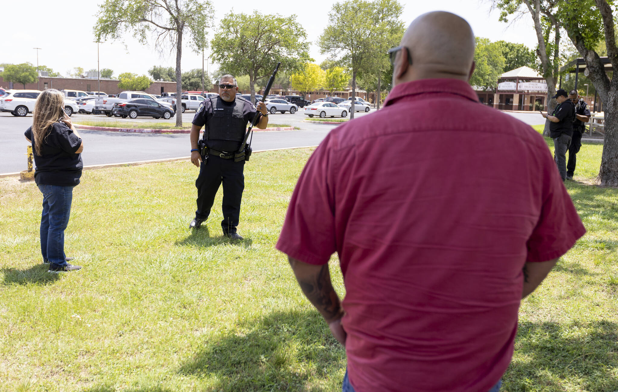 A law enforcement officer speaks with people outside Uvalde High School after shooting a was reported earlier in the day at Robb Elementary School on Tuesday in Uvalde, Texas. (William Luther/The San Antonio Express-News via AP)