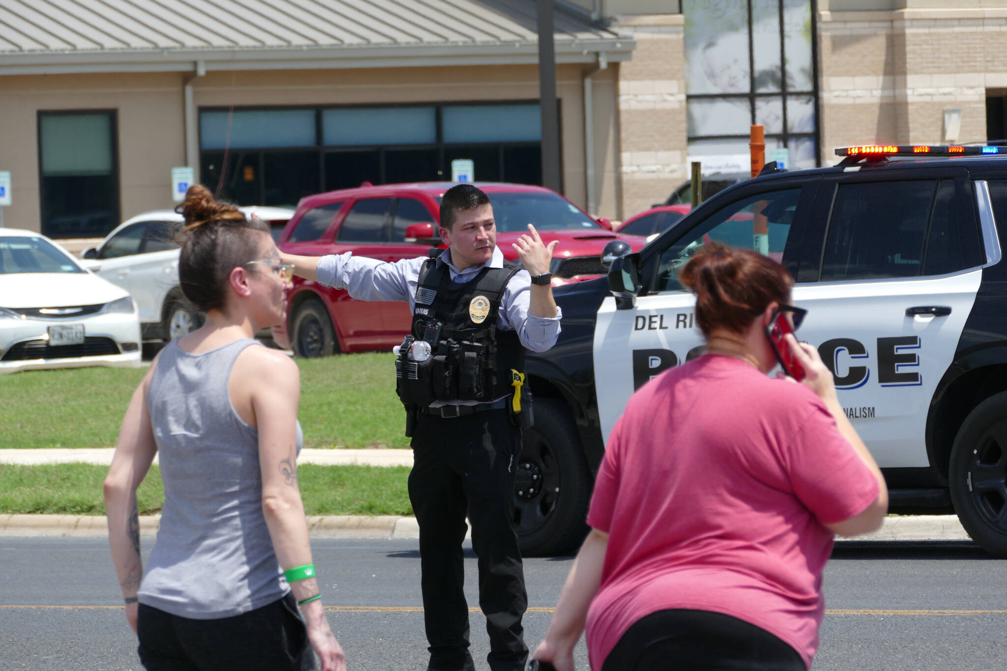 A law enforcement officer helps people cross the street at Uvalde Memorial Hospital after a shooting was reported earlier in the day at Robb Elementary School on Tuesday in Uvalde, Texas. (Billy Calzada/The San Antonio Express-News via AP)