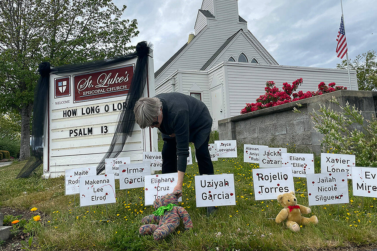 Matthew Nash/Olympic Peninsula News Group

The Rev. ClayOla Gitane, rector at St. Luke’s Episcopal Church, places signs and teddy bears in memory of the 21 victims of Tuesday's mass shooting in Robb Elementary School in Uvalde, Texas.