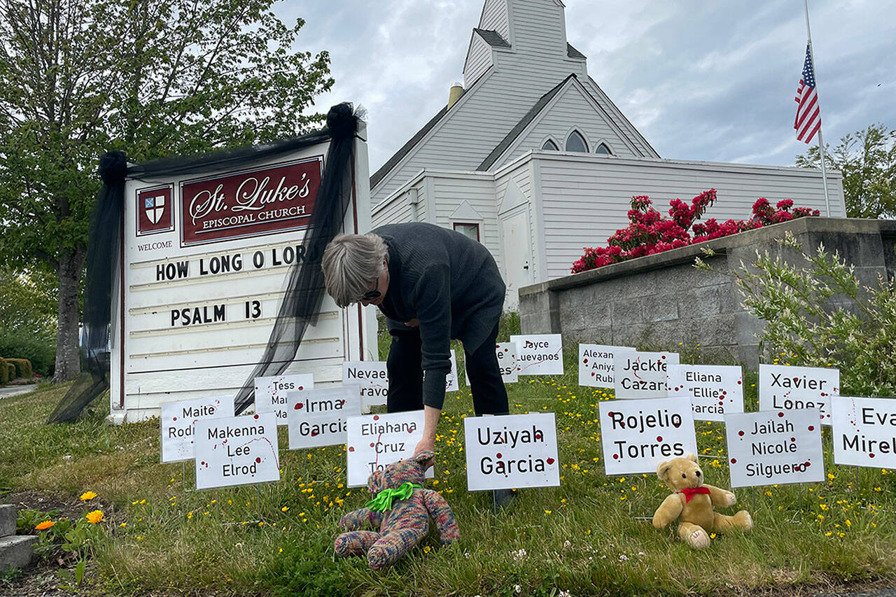 The Rev. ClayOla Gitane, rector at St. Lukes Episcopal Church, places signs and teddy bears in memory of the 21 victims of Tuesdays mass shooting at Robb Elementary School in Uvalde, Texas. (Matthew Nash/Olympic Peninsula News Group)