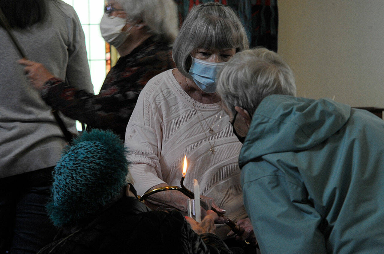 Pat Rublaitus helps light candles for a prayer service on Friday inside St. Luke’s Episcopal Church in Sequim for the victims of the Robb Elementary School shooting in Uvalde, Texas. About 40 people attended to pray and sing for the teachers and students and their families. Participants were encouraged to write prayers on cloth strips to be attached to a fence outside the church. The interfaith service was sponsored by St. Luke’s, Dungeness Valley Lutheran Church and Trinity United Methodist Church. (Matthew Nash/Olympic Peninsula News Group)