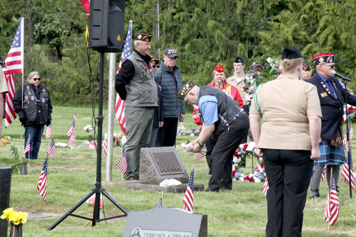 Korean War Veteran Mark Lomax lays flowers on a gravesite during a ceremony Monday at Mt. Angeles Cemetery. He represented one of several branches of the military who laid wreaths in memoriam. (Dave Logan/For Peninsula Daily News)
