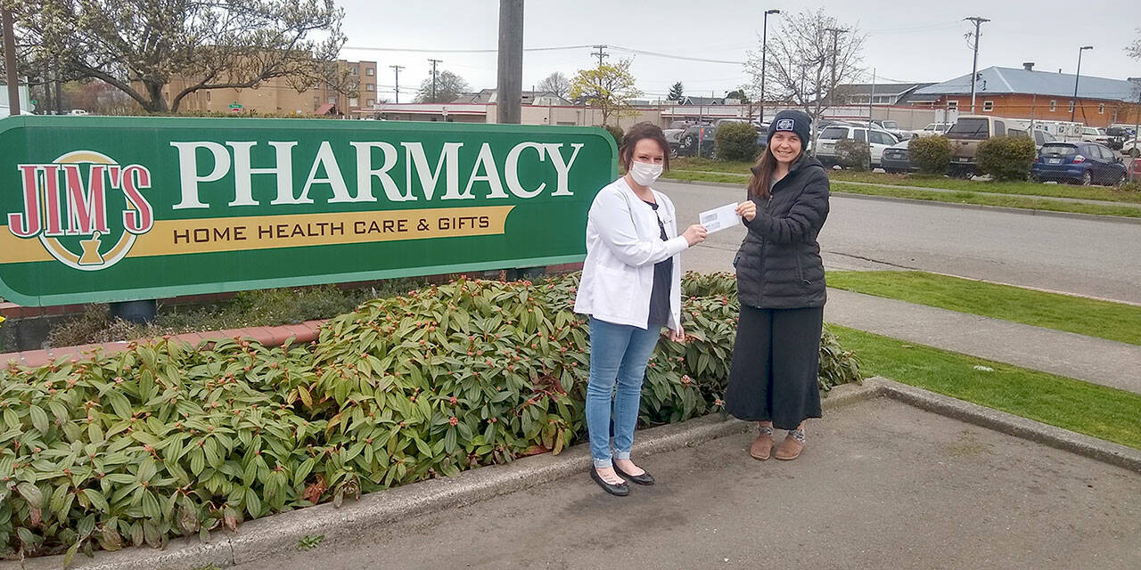 Rachel Anderson, left, from Jim’s Pharmacy, delivers a check Alexi Nelson, the food bank’s community engagement coordinator.