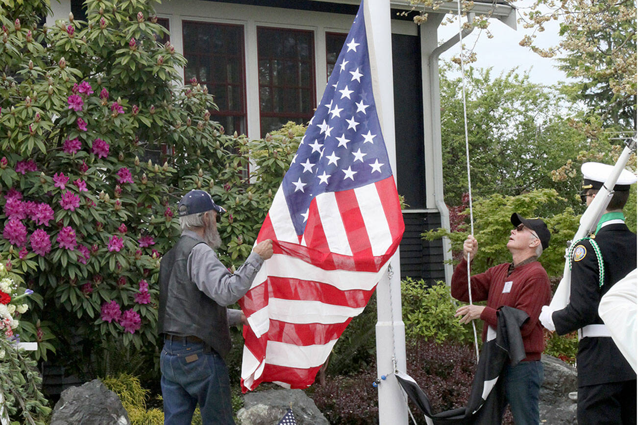 David Logan/for Peninsula Daily News 

Raising their late father’s U.S. Flag over the Captain Joseph House on Memorial Day are Walter Johnson, left, and Norris Johnson, right.