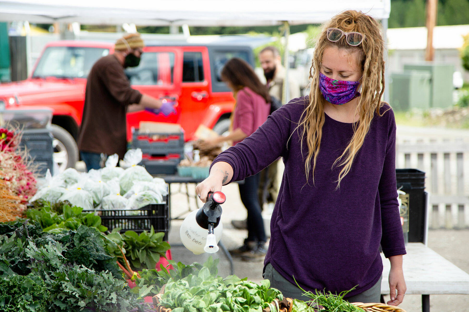 Emma Erickson with Red Dog Farm keeps produce fresh at an earlier Chimacum Farmers Market. (Andrew Wiese)
