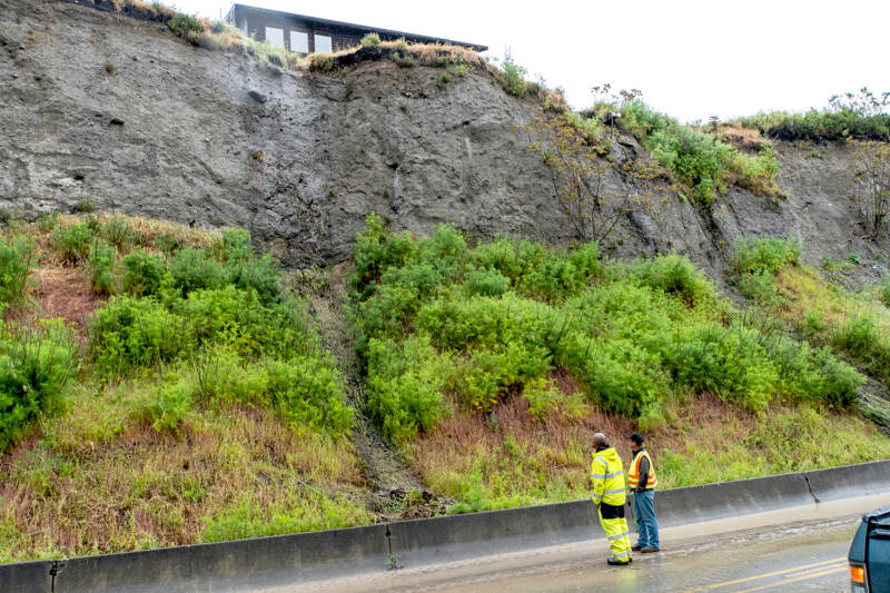 Port Townsend city employee Rafe Thornton, in yellow slicker, and an unidentified man, survey a landslide from Washington Street that fell onto Water Street and closed access to the ferry terminal and other locations in downtown Port Townsend due to heavy rainfall Sunday afternoon. Jefferson County Emergency Management issued a warning at 1:55 p.m. that the street was closed and alternate routes were necessary. A city dumptruck hauled away a load of mud and debris that was blocking the street. Further cleanup was needed before the street could be opened. (Steve Mullensky/for Peninsula Daily News)