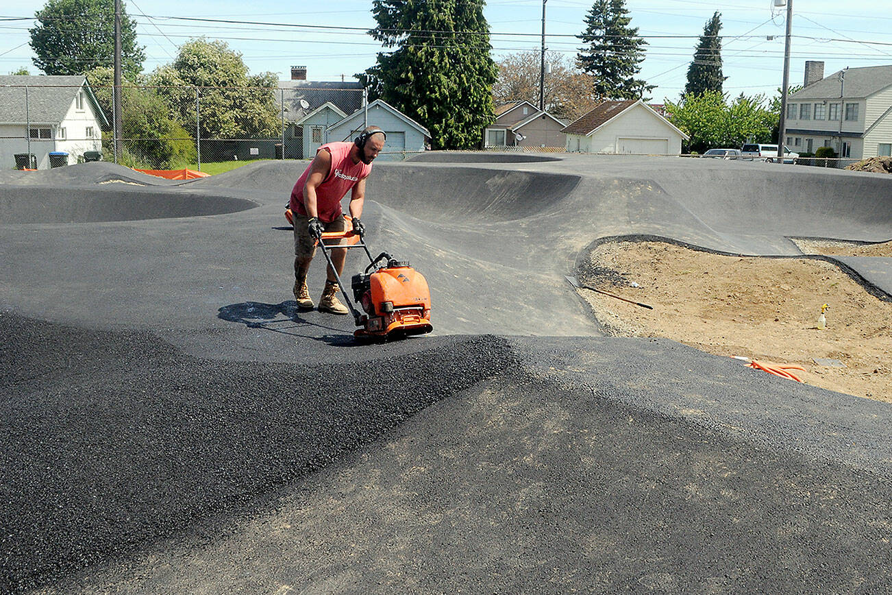 Keith Thorpe/Peninsula Daily News
T.J. Farris of Bakersfield, Calif., an employee of the Flims, Swittzerland-based Velosolutions, uses a compactor on Tuesday to create a lane surface on an asphalt portion of a pump track being built at Erickson Playfield in Port Angeles. The track, designed primarily for bicycles and other wheeled play vehicles, is being constructed by the Port Angeles Parks & Recreation Department in conjunction the Lincoln Park BMX Association with funding from a $350,000 grant from the state Recreation and Conservation Office, $100,000 in lodging tax grants from the city and Clallam County, business sponsorships, individual and community donations and a grant from the Christopher and Dana Reeve Foundation. It is expected to be completed by late June or early July.