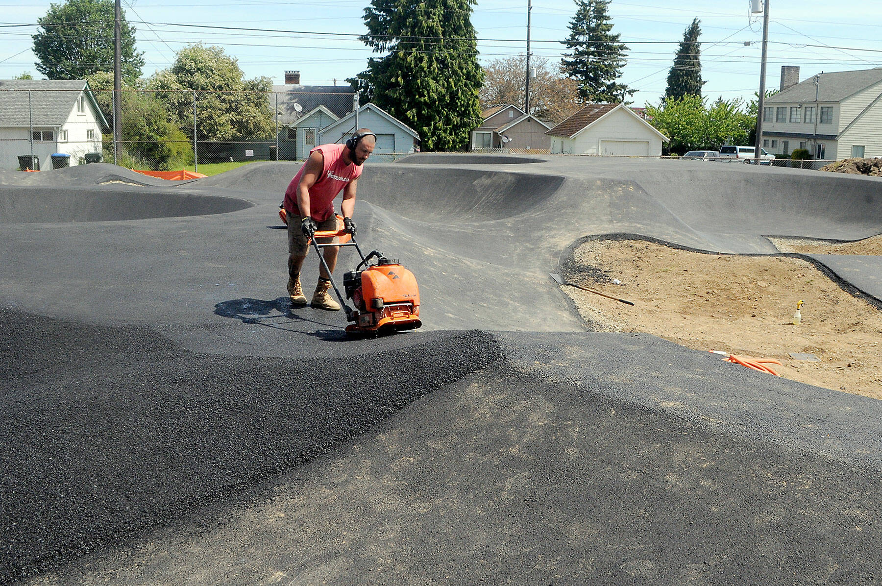 T.J. Farris of Bakersfield, Calif., an employee of the Flims, Switzerland-based Velosolutions, uses a compactor on Tuesday to create a lane surface on an asphalt portion of a pump track being built at Erickson Playfield in Port Angeles. (Keith Thorpe/Peninsula Daily News)