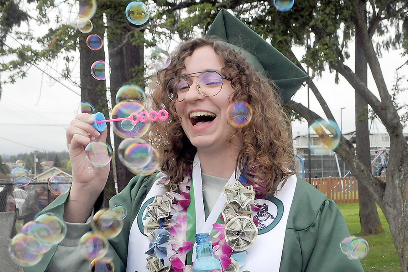Port Angeles High School graduate Sage Hunter blows bubbles prior to Friday’s commencement ceremony at Port Angeles Civic Field. A total of 236 seniors made up the school’s Class of 2022. (Keith Thorpe/Peninsula Daily News)