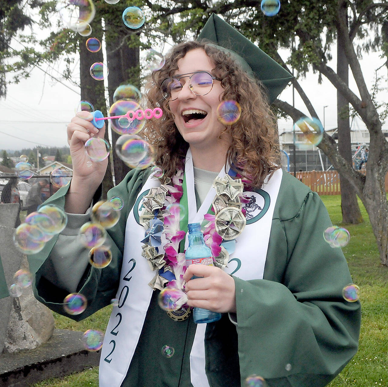 Port Angeles High School graduate Sage Hunter blows bubbles prior to Friday’s commencement ceremony at Port Angeles Civic Field. A total of 236 seniors made up the school’s Class of 2022. (Keith Thorpe/Peninsula Daily News)