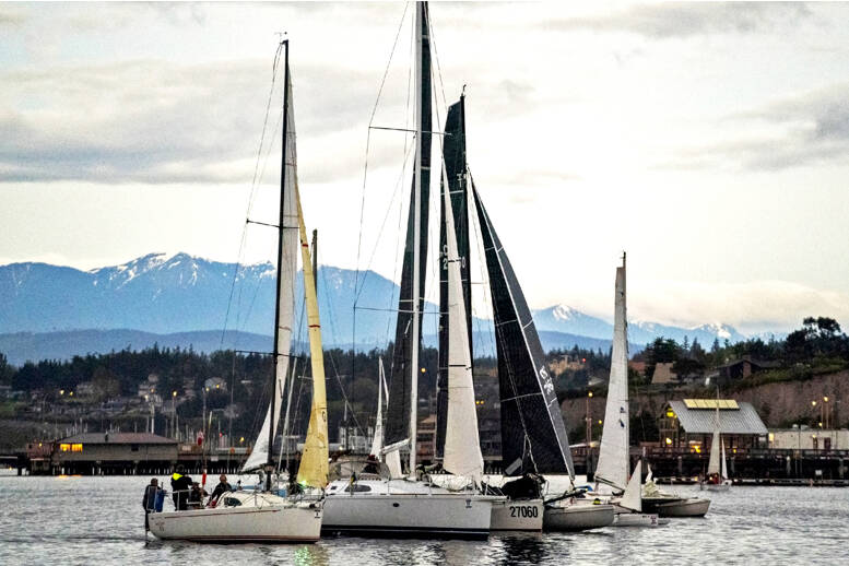 With the snow-clad Olympic Mountains in the background and the patriotic strains of the Ukrainian national anthem playing over loudspeakers, these six sailboats of various shapes and sizes aim for the start line to embark on the Race 2 Alaska at 5 a.m. Monday morning in Port Townsend. With only the sound of wind in the sails (no motors are allowed), oars and paddles digging into the water and waves splashing against hulls, the 38 full race teams and the 12 proving ground teams face a formidable 750 miles of sometimes calm, sometimes stormy but always-dangerous ocean water before reaching the final destination of Ketchikan, Alaska. The winning team gets $10,000 nailed to a post while the second-place team races for a set of steak knives. The first stop is Victoria, B.C., where the teams will prove their mettle and get ready for the 710-mile stretch to Ketchikan, which gets underway on Thursday at noon in Victoria Harbour. (Steve Mullensky/for Peninsula Daily News)