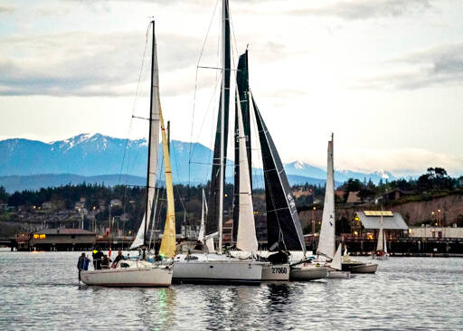 With the snow-clad Olympic Mountains in the background and the patriotic strains of the Ukrainian national anthem playing over loudspeakers, these six sailboats of various shapes and sizes aim for the start line to embark on the Race 2 Alaska at 5 a.m. Monday morning in Port Townsend. With only the sound of wind in the sails (no motors are allowed), oars and paddles digging into the water and waves splashing against hulls, the 38 full race teams and the 12 proving ground teams face a formidable 750 miles of sometimes calm, sometimes stormy but always-dangerous ocean water before reaching the final destination of Ketchikan, Alaska. The winning team gets $10,000 nailed to a post while the second-place team races for a set of steak knives. The first stop is Victoria, B.C., where the teams will prove their mettle and get ready for the 710-mile stretch to Ketchikan, which gets underway on Thursday at noon in Victoria Harbour. (Steve Mullensky/for Peninsula Daily News)
