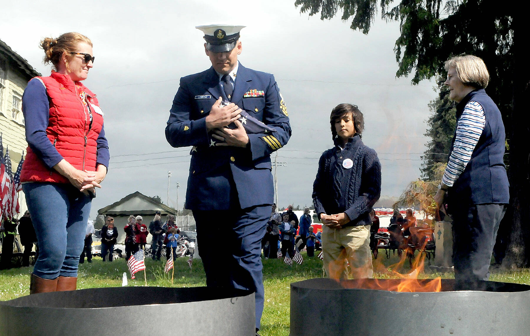 U.S. Coast Guard Chief Petty Officer Shane Thompson, accompanied by his son, Malachi Thompson, 10, a member of Junior American Citizens, carries a retiring flag for incineration on Tuesday at the Northwest Veterans Service Center in Port Angeles on Flag Day. (Keith Thorpe/Peninsula Daily News)