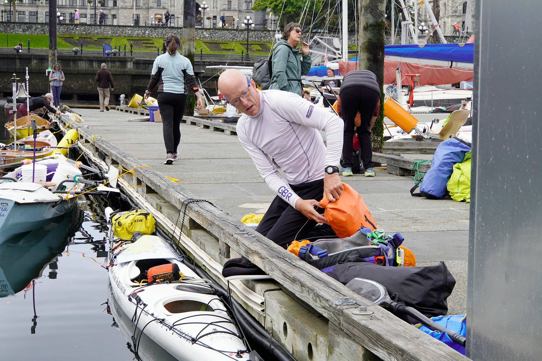 Bob McCall, from Great Britain, loads his kayak with supplies he will need for his 710-mile journey to Ketchikan, Alaska, during the 2022 Race 2 Alaska, which got underway at noon Thursday from Victoria Harbour. A self-described tracker junkie since the first race, McCall decided to enter the race in 2020 and ordered a kayak built in Victoria, but COVID-19 hit and canceled everything. This is the first time he was able to enter and he is looking forward to the adventure. (Steve Mullensky/for Peninsula Daily News)
