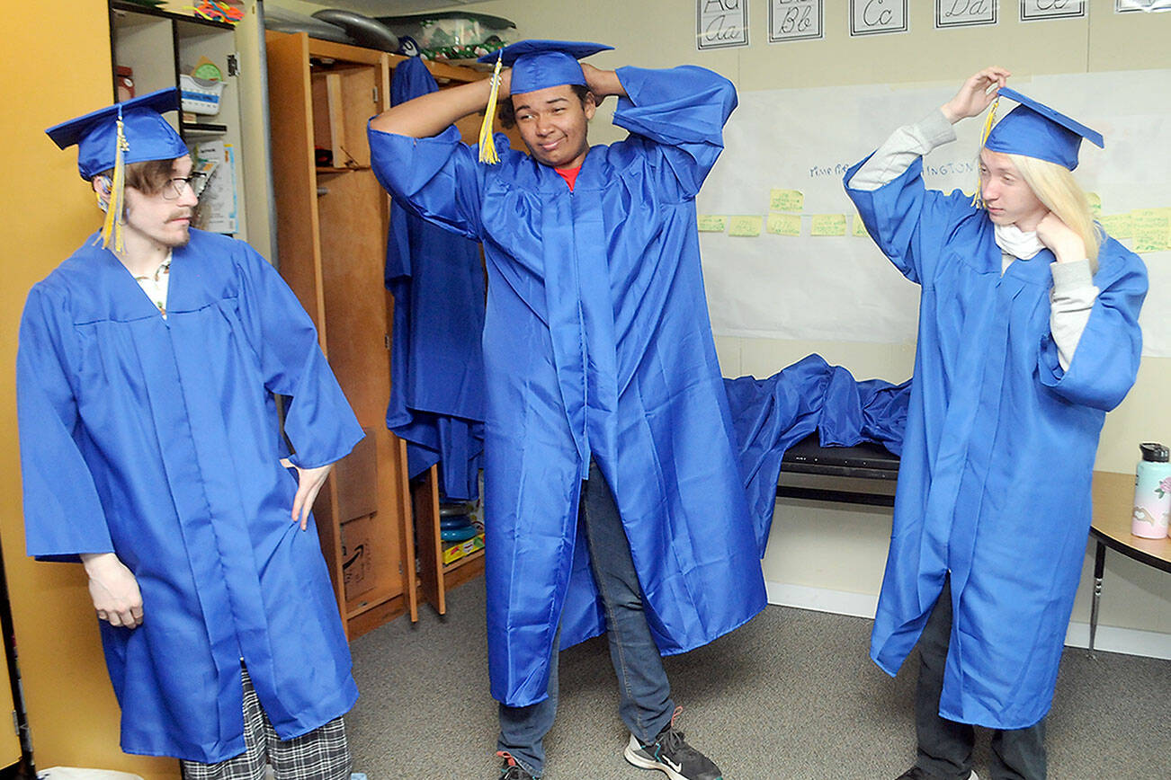 Keith Thorpe/Peninsula Daily News
Crescent High School graduates, from left, Randy Lee, Isaac Elliott and Cody Larsen don their caps and gowns prior to Saturday's commencement on the school's athletic field in Joyce. A total of 13 seniors made up the Crescent Class of 2022.