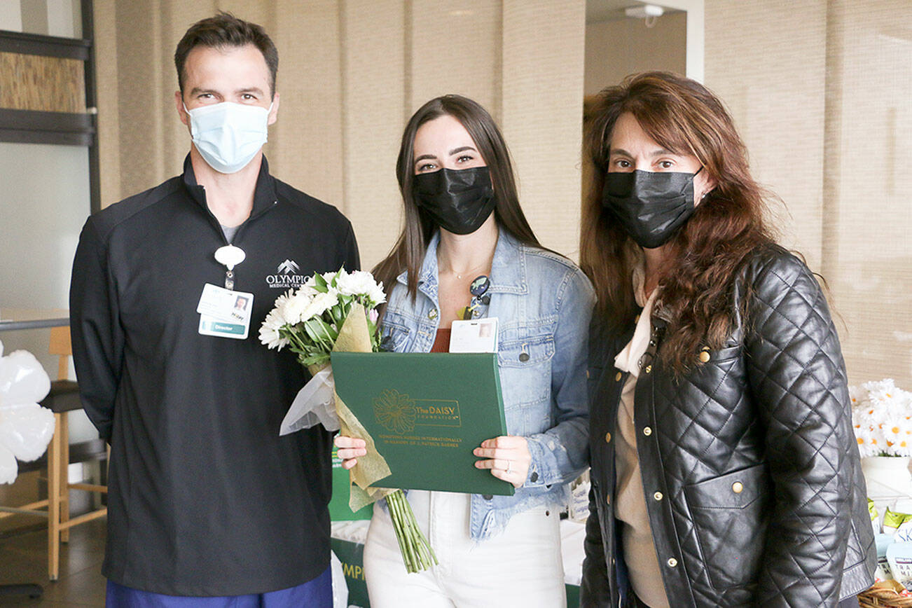 Aaron Possin, left, and Vickie Swanson, right, present a DAISY Award to Elizabeth Hornsey, an RN in Olympic Medical Center's emergency department.