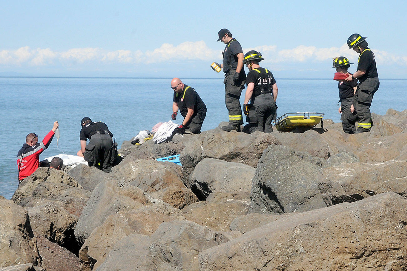 Port Angeles firefighters and paramedics come to the aid of a person who fell from the riprap and became trapped between rocks for three hours on Ediz Hook in Port Angeles on Thursday. (Keith Thorpe/Peninsula Daily News)