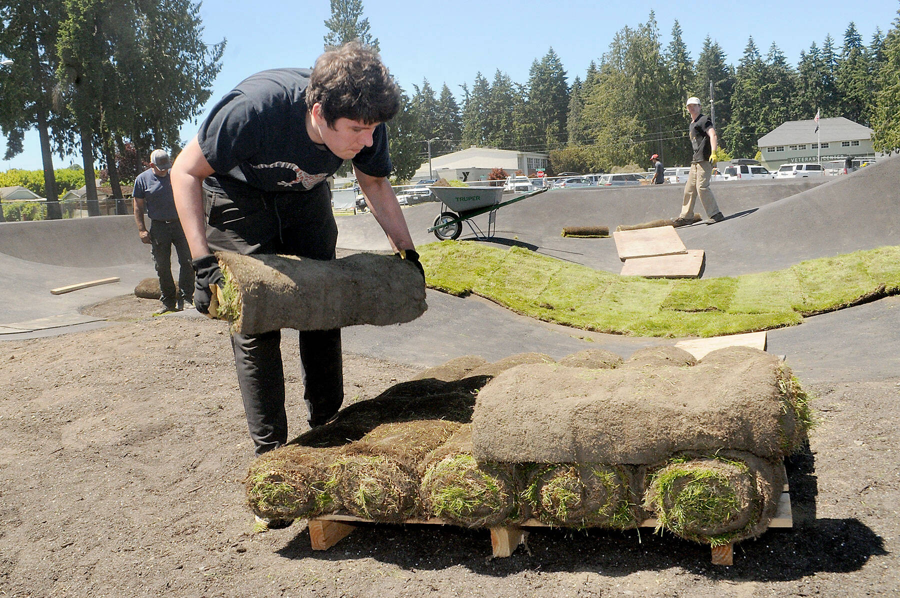 Volunteer Eric Lalonde, 15, of Port Angeles carries a roll of sod during a community work day on Friday at the pump track being built at Erickson Playfield in Port Angeles. (Keith Thorpe/Peninsula Daily News)