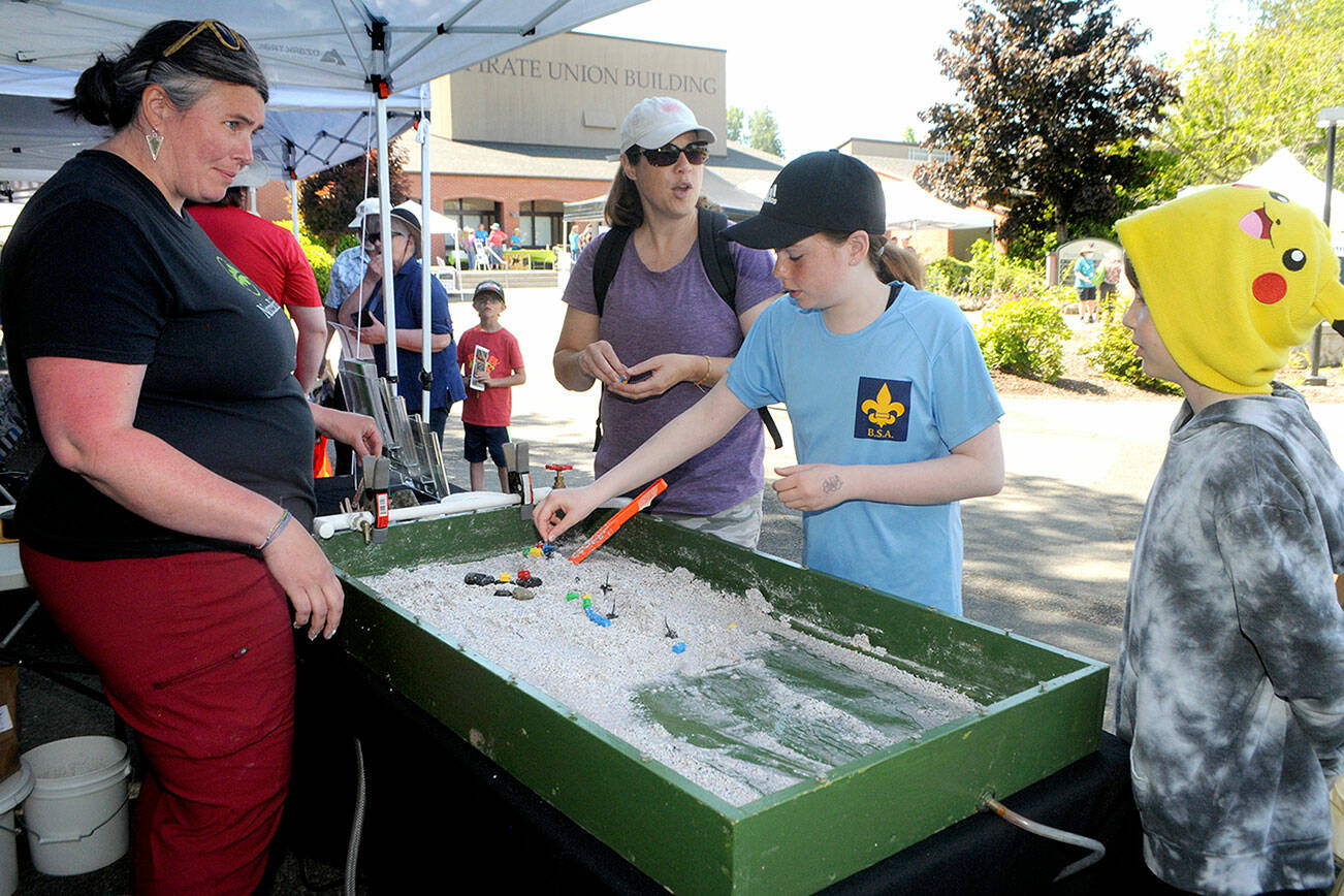 Emily Volz of NatureBridge, left, explains how erosion changes the landscape as members of the Jacobs family of Port Angeles, from left, Monica, Emerson, 11, and Jack, 9, create a miniature flood plain during the Forever StreamFest environmental fair at Peninsula College in Port Angeles. The Saturday event, hosted by the Port Angeles Garden Club, featured a variety of displays and educational activities, along with music and guest speakers, geared toward protection of the air, water, forests, land and wildlife. (Keith Thorpe/Peninsula Daily News)