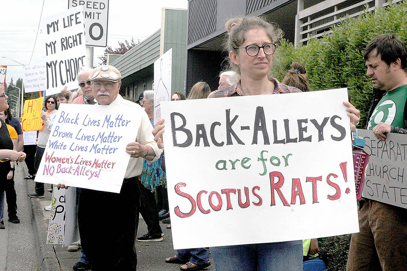 Keith Thorpe/Peninsula Daily News Tim Wheeler of Sequim, center left, and Lillian Easton of Port Angeles, hold signs in favor of reproductive rights during a rally that began at Planned Parenthood in Port Angeles and ended up at the Clallam County Courthouse. The pair were among about 80 people protesting on Wednesday against the recent ruling by the U.S. Supreme Court to overturn the Roe vs. Wade case that granted the right to an abortion in the United States.