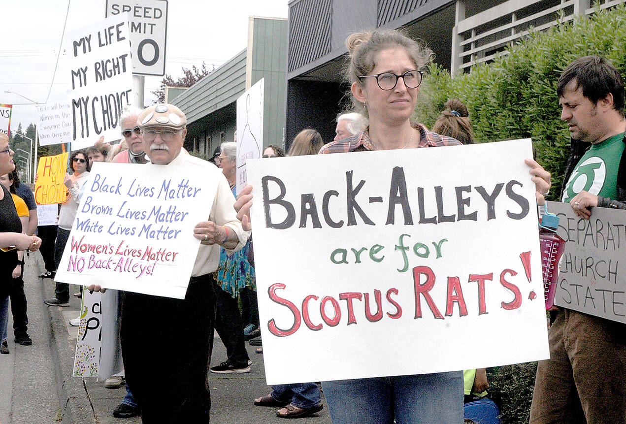 Keith Thorpe/Peninsula Daily News Tim Wheeler of Sequim, center left, and Lillian Easton of Port Angeles, hold signs in favor of reproductive rights during a rally that began at Planned Parenthood in Port Angeles and ended up at the Clallam County Courthouse. The pair were among about 80 people protesting on Wednesday against the recent ruling by the U.S. Supreme Court to overturn the Roe vs. Wade case that granted the right to an abortion in the United States.