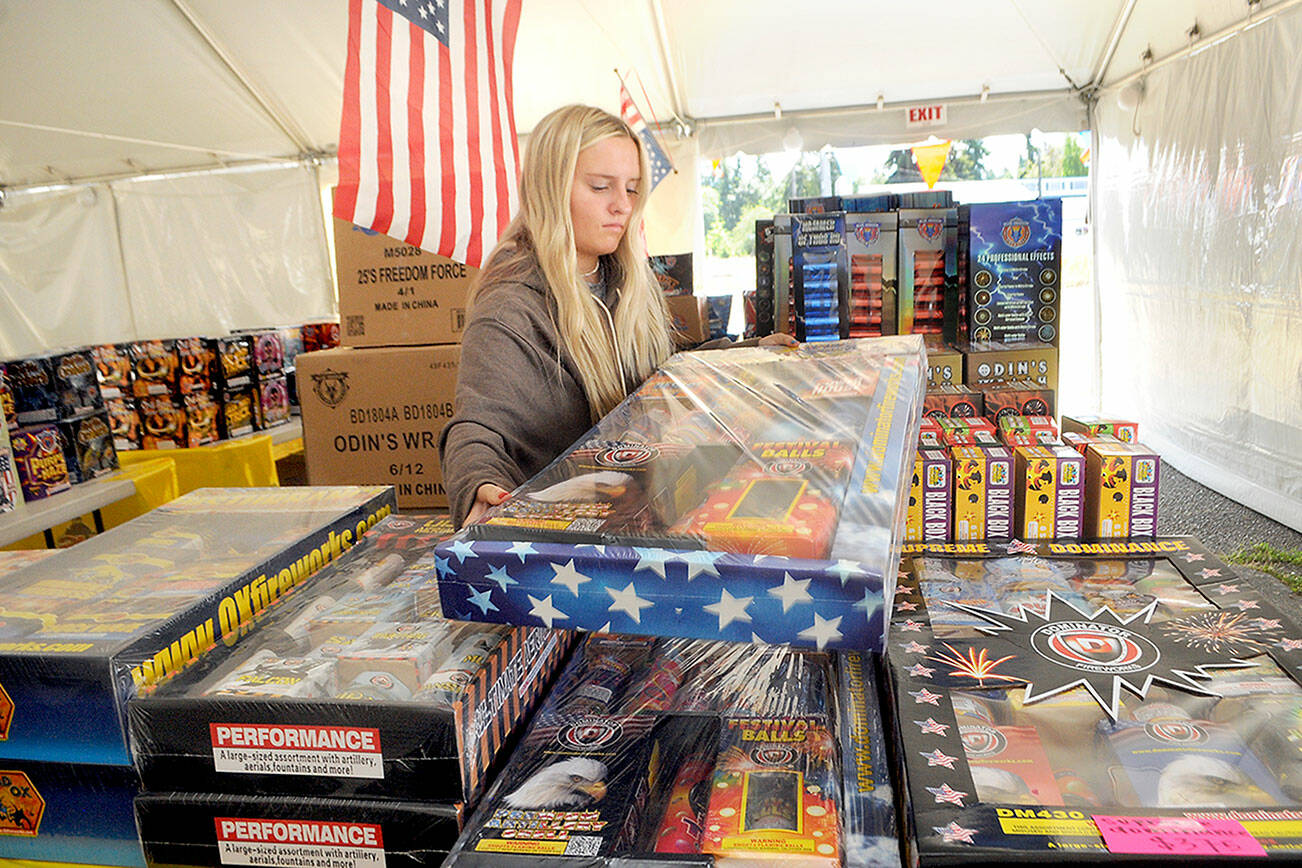 Keith Thorpe/Peninsula Daily News
Kira Watson replenishes inventory at the Olympic Fireworks stand at U.S. Highway 101 and Gales Street on the east side of Port Angeles on Thursday.